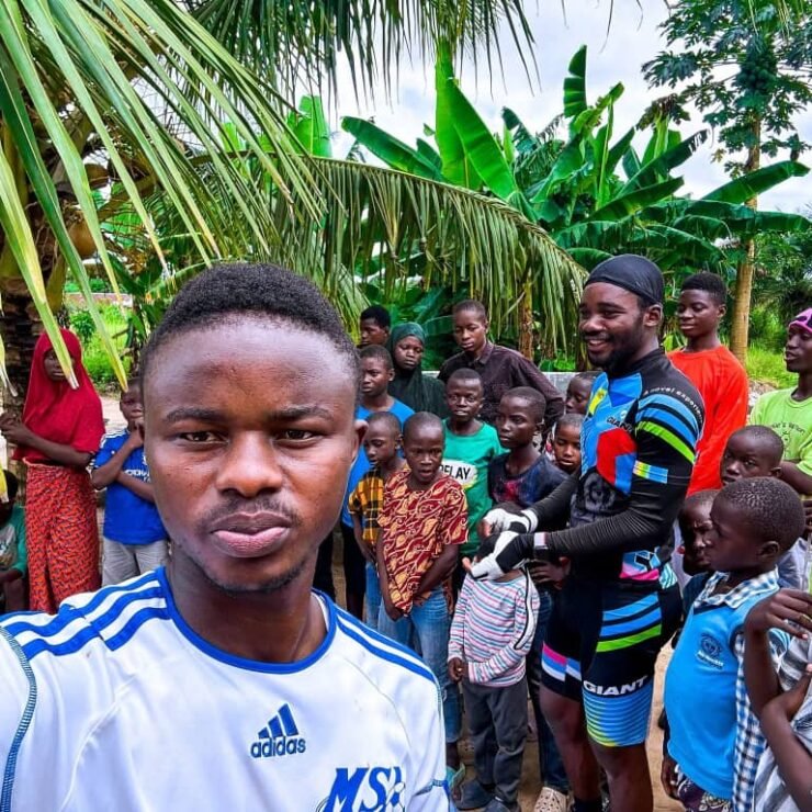 Emmiwuks standing with children benefiting from donations raised during his NIG2USA charity bicycle journey