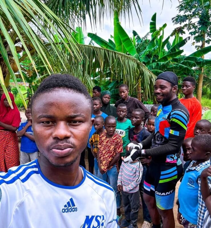 Emmiwuks standing with children benefiting from donations raised during his NIG2USA charity bicycle journey